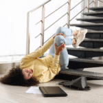 Woman lying on stairs with a laptop and papers, contemplating average slip and fall settlements in Texas.