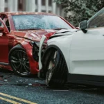 A red car and a white car collide head-on, illustrating a traffic accident scenario.