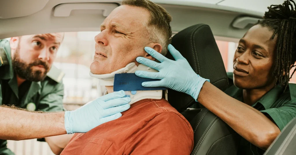 A doctor examines a man in a car, discussing whiplash injuries from a recent car accident